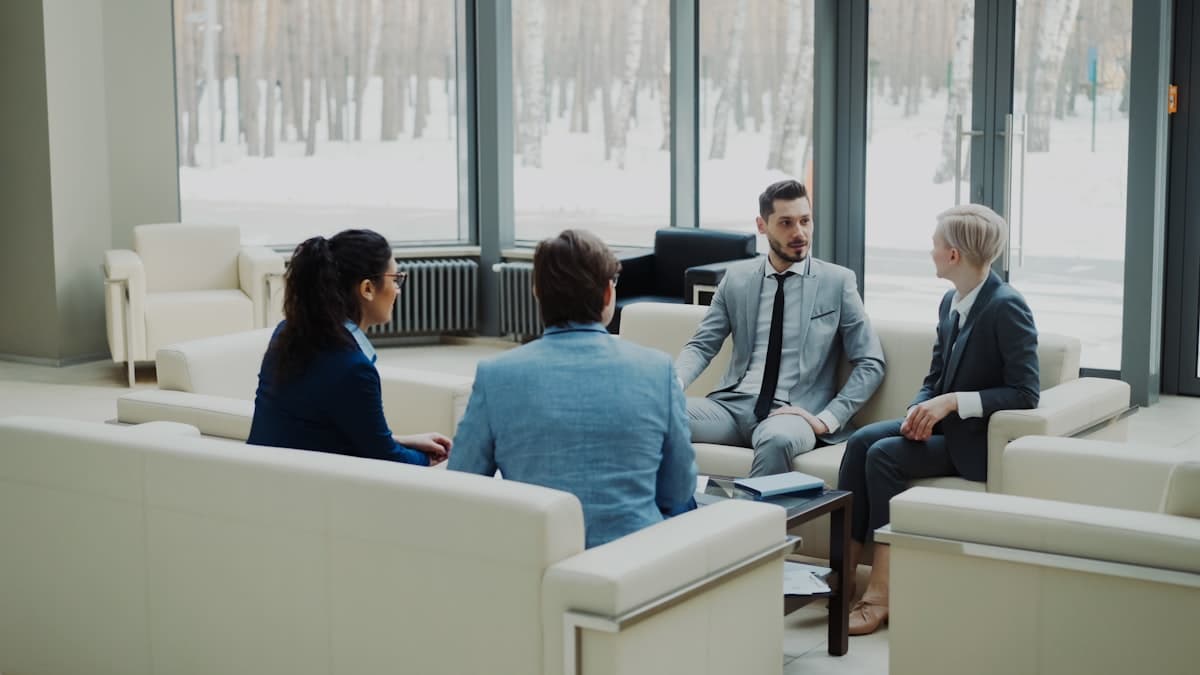 Four colleagues talking around a low table in a bright office lounge