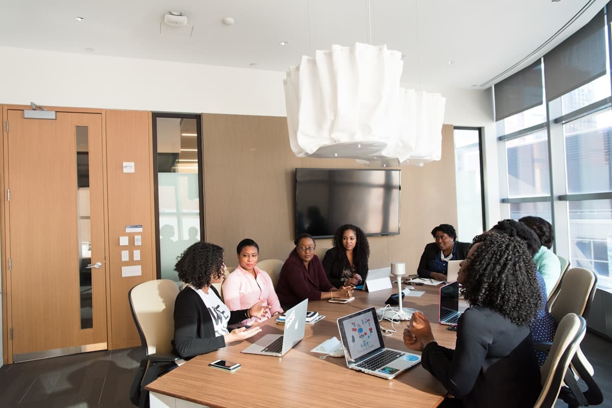 A team in a boardroom reviewing figures together on laptops